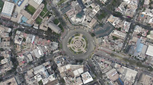 Cars driving around ovalo gutierrez roundabout in miraflores district, lima, peru, creating a dynamic urban scene