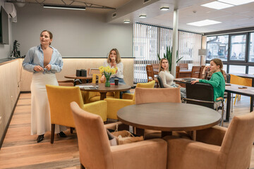 Meeting Women Discussion: Daytime office meeting features four women discussing business in a modern lounge area.