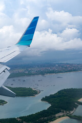 Aerial view from plane approaches Bali, revealing a sweeping view of tropical coastline, scattered...