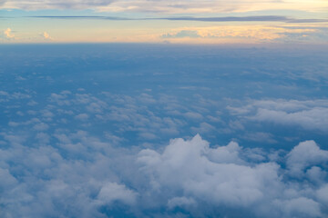 Naklejka premium Peaceful aerial view of soft clouds stretching to the horizon under a pastel sky during flight, capturing the calm beauty of the atmosphere at high altitude.