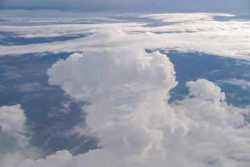 Towering cumulonimbus cloud rises dramatically above the landscape, viewed from an airplane in...