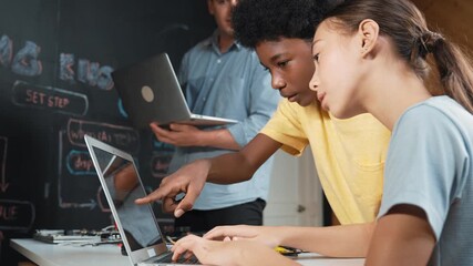 Group of diverse student working together to write program. Multicultural children coding or programming program while teacher pointing at screen at explain mistake point at STEM class. Edification - Powered by Adobe