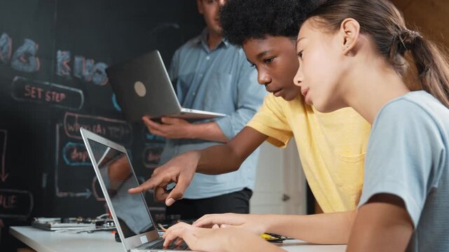 Group of diverse student working together to write program. Multicultural children coding or programming program while teacher pointing at screen at explain mistake point at STEM class. Edification - Powered by Adobe