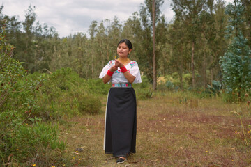 Indigenous otavalo woman wearing traditional clothes holding a flower in ecuadorian andes mountains