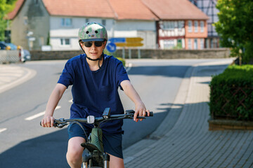 Teenager boy wearing helmet and sunglasses riding a bicycle in the city. Active lifestyle, urban youth, safety gear, outdoor fun, and healthy transportation