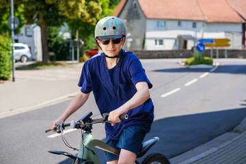 Teenager boy wearing helmet and sunglasses riding a bicycle in the city. Active lifestyle, urban youth, safety gear, outdoor fun, and healthy transportation