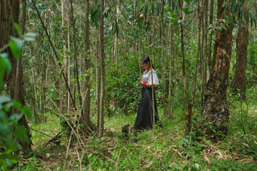 Indigenous woman walking through lush forest in traditional clothing
