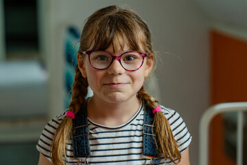Little girl with glasses and raindrops on her face, surprised expression. Child outdoors in rainy weather. Real life, real people, natural childhood, emotions, weather