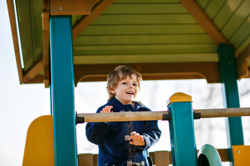 Child, little preschool boy on playground. Active kid exercising in school yard. Children play and...