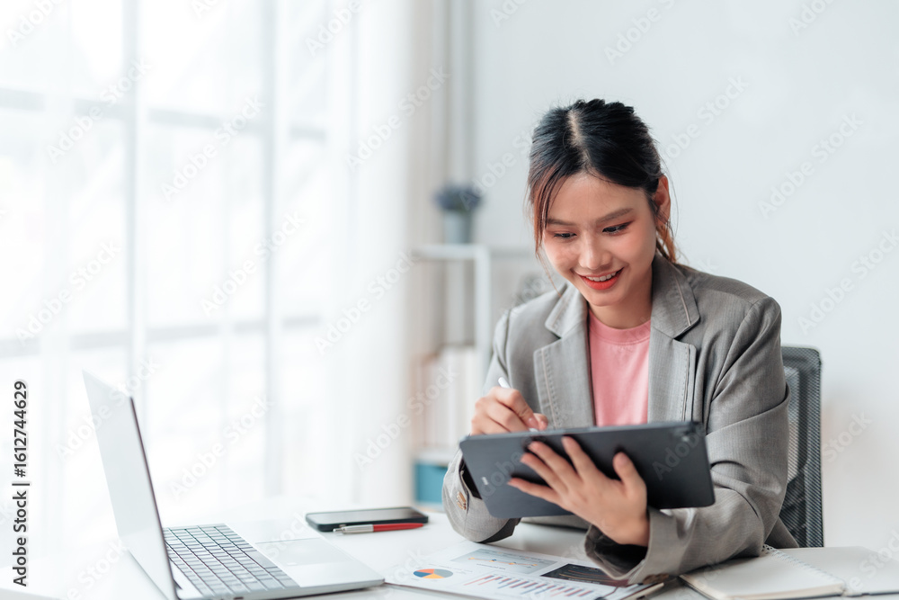 Aufkleber young office worker using tablet and stylus pen while working on a project in a bright and modern of