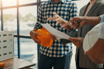 Architects and engineers are examining blueprints and discussing a building project during a...