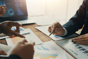 Business team analyzing financial charts and graphs showing company growth and discussing new...