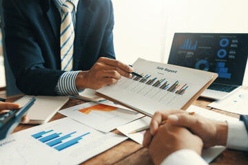 Business team discussing sales report using charts and graphs on a laptop during a meeting to...