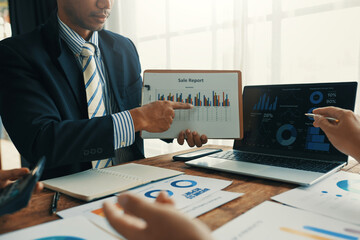 Business people discussing sales data during a meeting, pointing at charts and graphs displayed on...
