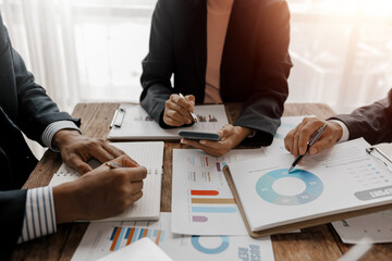 Business people working together analyzing financial reports with charts and graphs using...