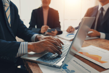 Business people are working on a laptop and analyzing financial charts and graphs during a...