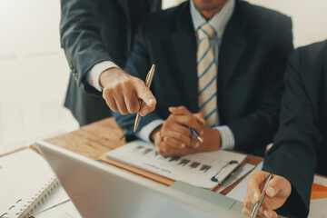 Business people are using a laptop and analyzing financial charts and graphs during a corporate...
