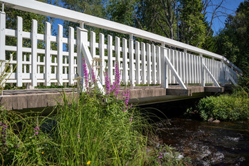 white wooden bridge with railing across stream in city park, Oulu Finland