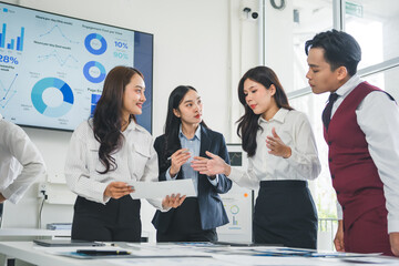Four Asian businesspeople are discussing marketing strategy during a meeting in a modern office,...