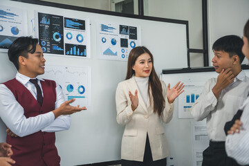 Group of young Asian businesspeople discussing company strategy during a meeting in a modern office...
