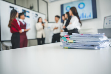 Stacked documents adorned with colorful sticky notes resting on a white table in an office meeting...