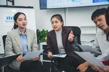 Group of asian businesspeople sharing documents and discussing during a working meeting in a modern...