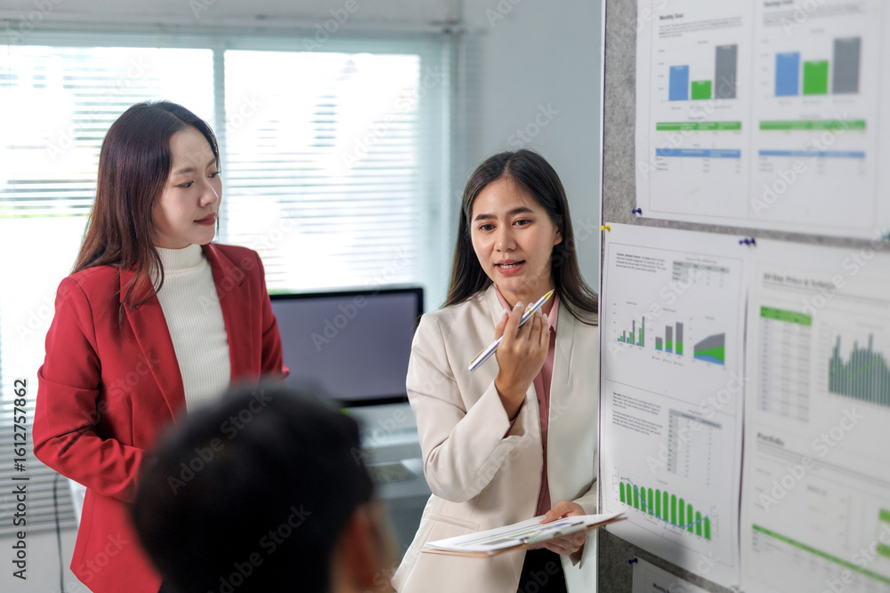 Poster asian businesswomen explaining charts and reports on a whiteboard, using pens and documents during a