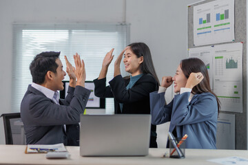 Happy business team exchanging high fives in the office, celebrating successful project completion,...