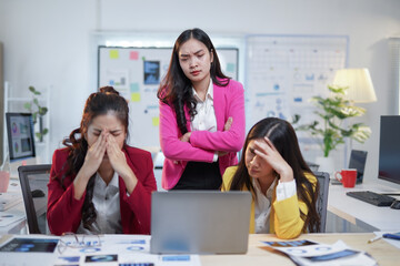 Three Asian businesswomen feeling overwhelmed and stressed, analyzing marketing data on a laptop in...