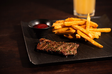 Grilled Beef Steak with French Fries and Ketchup on Black Plate