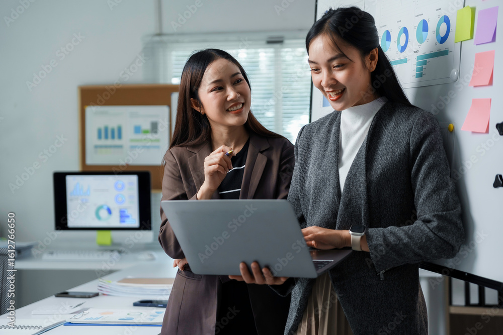 Aufkleber two smiling asian businesswomen are discussing and working together using a laptop in a modern offic