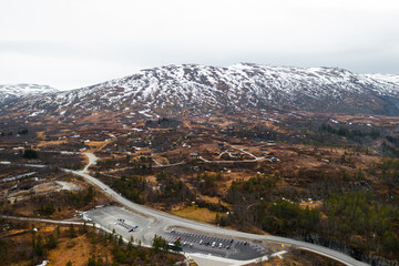 Magnificent Voringsfossen waterfall plunges into deep rugged canyon flanked by rocky cliffs. Winding road and sparse vegetation complete landscape