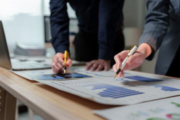 Business colleagues reviewing financial reports and analyzing market trends using pens, working...