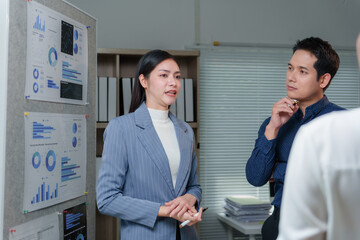 Asian businesswoman holding a pen while presenting marketing data through graphs and charts to...