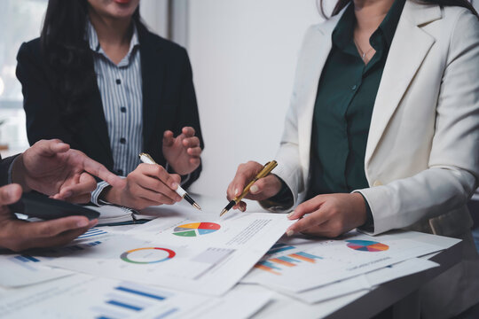 Business team analyzing financial documents using data charts and graphs, making investment plan and discussing new marketing strategy at meeting - Powered by Adobe