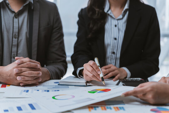 Business people reviewing financial reports and analyzing company performance using charts, graphs, and calculators during a meeting, demonstrating teamwork and data driven decision making