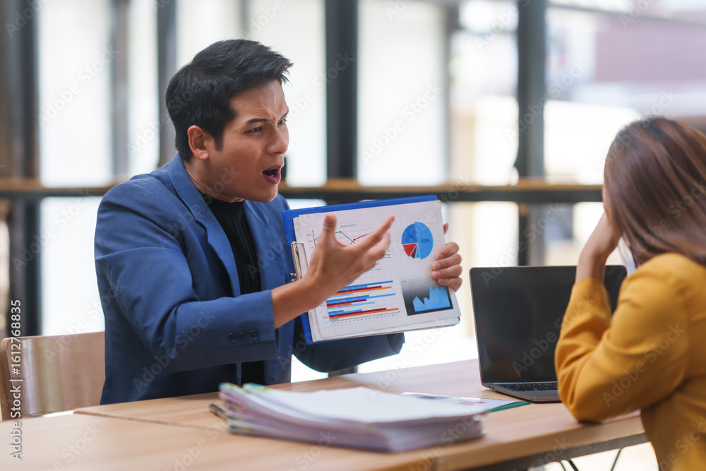 Poster asian businessman displaying a negative financial chart while arguing with a stressed colleague at a