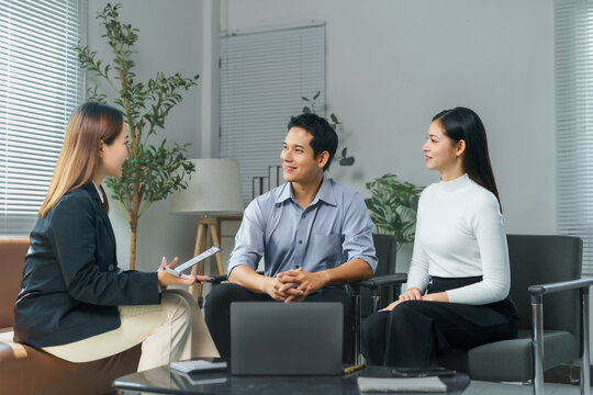 Financial advisor holding digital tablet and consulting young asian couple about investment plan during meeting in office, investment and finance concept