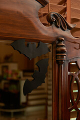 Paper bat decorations hanging on a vintage wooden mirror for Halloween.