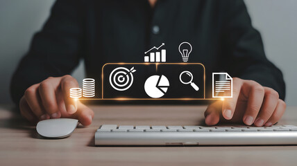 Hands using a computer keyboard and mouse interacting with a digital interface displaying business growth and financial data icons