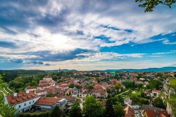 Fototapeta premium Scenic Small Town with Red Roofs Surrounded by Hills and Greenery