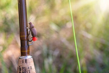 Fly rod and fly REDTAG close-up. Fishing on a mountain river.