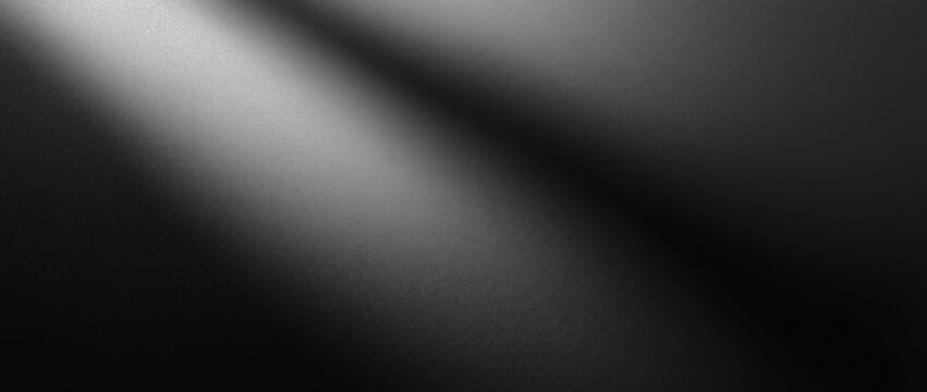 Close-up of a textured black surface with a subtle diagonal light gradient shining across it.