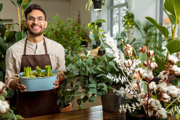 Man in apron holding a flower bed with succulents