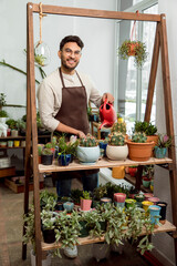 Flower shop assistant watering cactuses and looking contented