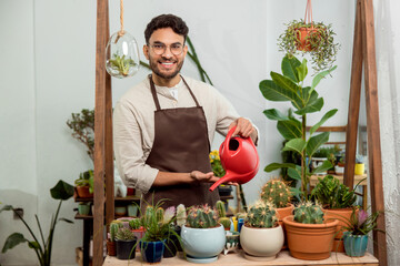 Flower shop assistant watering cactuses and looking contented