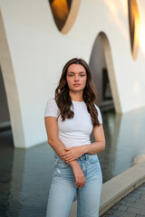 Young woman posing in front of modern building with water feature