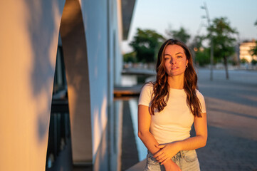 Young woman posing in golden hour light near modern building