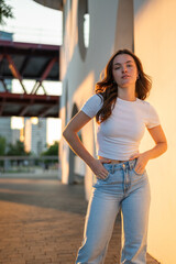 Young woman posing with hands in pockets at sunset in the city