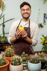 Smiling male flower shop assistant showing a small cactus